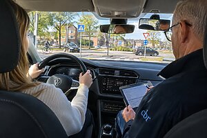 Examinator beoordeelt leerling tijdens praktijkexamen auto