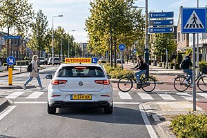 Lesauto houdt rekening met fietsers en voetgangers bij een Nederlandse verkeerssituatie